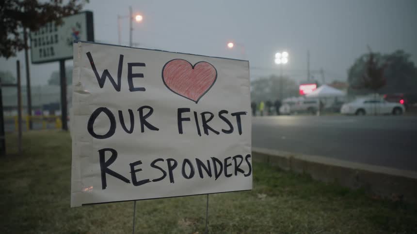 Sign expressing love for first responders is staked on lawn near highway at night