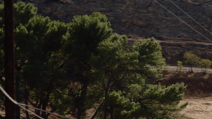 Fire engine drives along highway past burned fields