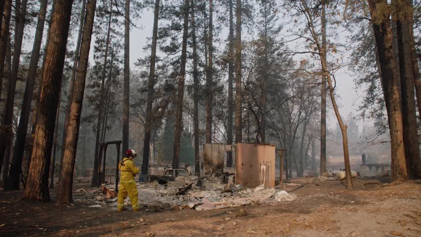 A firefighter stands near the debris of a fire