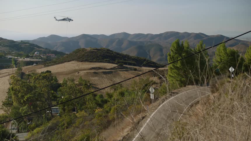 The helicopter drags a balloon over the mountains