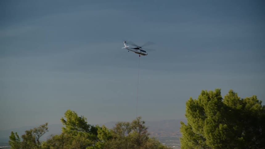 The helicopter flies with water over the mountains