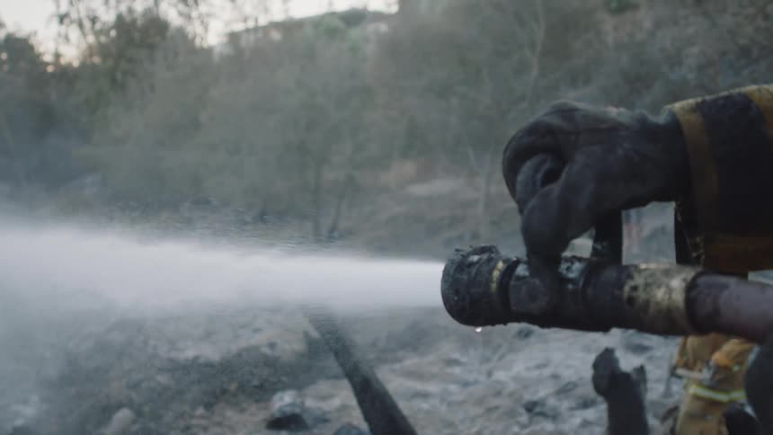 A firefighter is aiming a hose