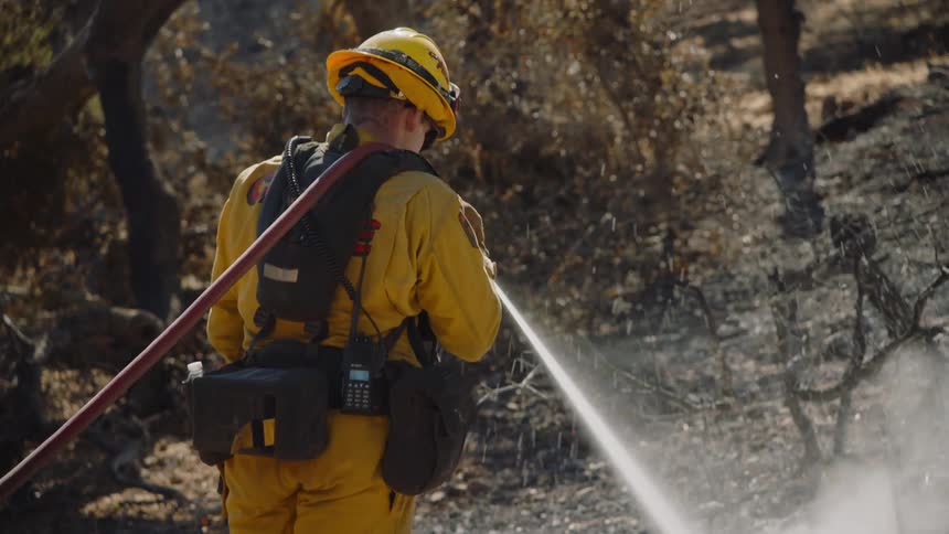 A man shoots a water hose on the fire