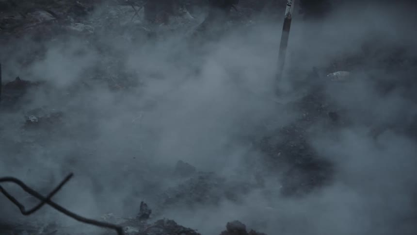 Firefighter stands with tool on smoking burnt ground