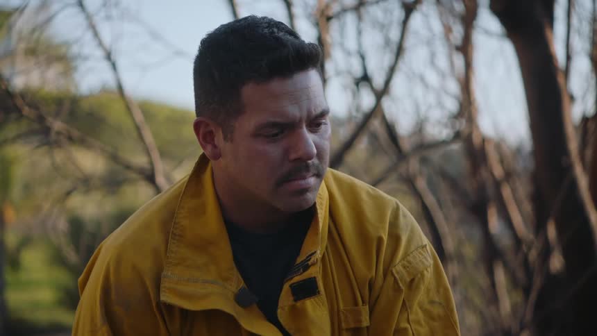 A fireman sitting looking toward the ground contemplatively