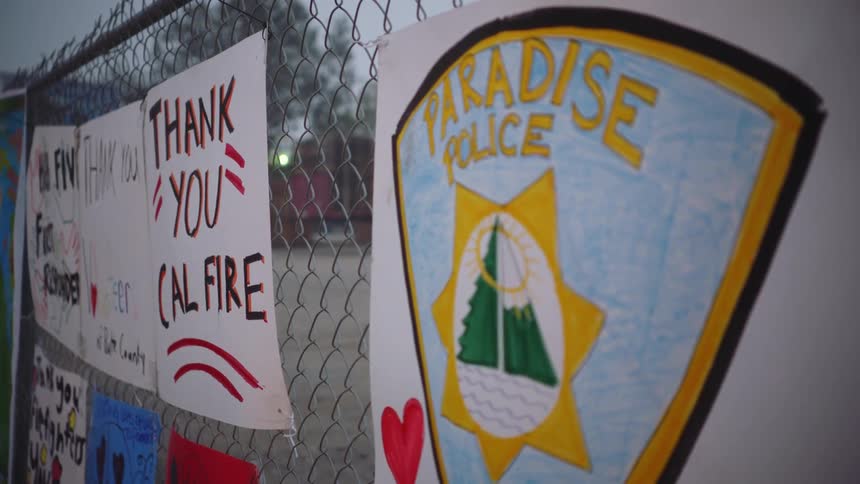 Posters attached to chain link fence express thanks to firefighters and police