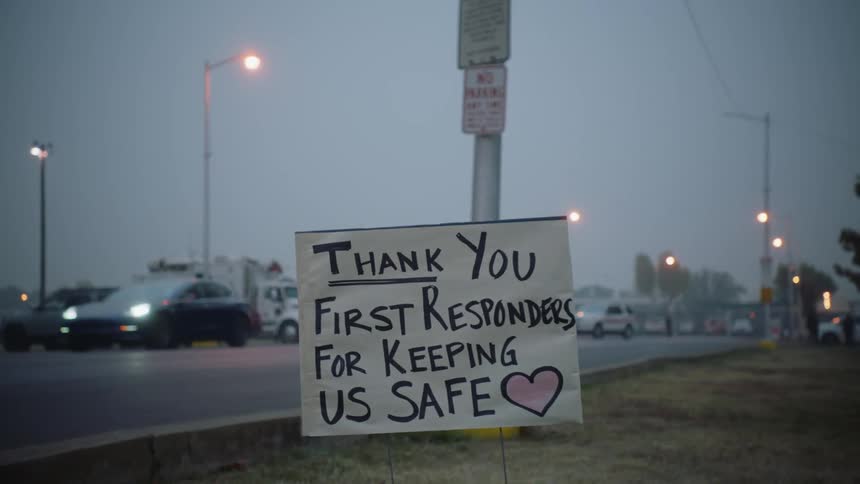 A hand written sign on the edge of the road as cars go by
