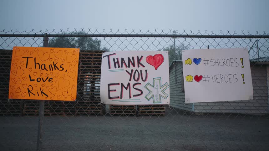 Three hand written signs on a chain linked fence outside