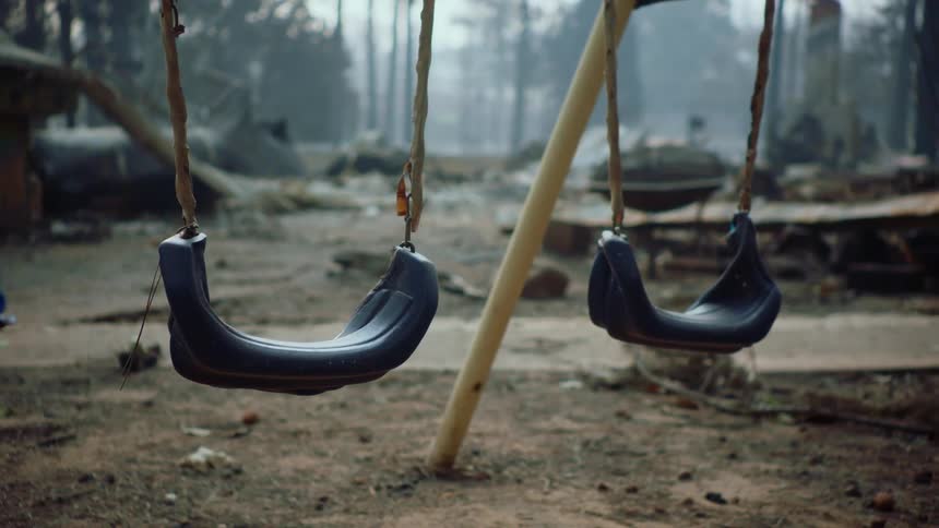 A swing set with two blue swing seats on a dirt playground