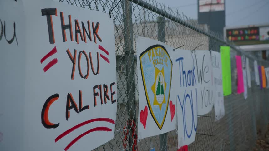 Handmade signs thanking california firefighters and police are hanging on a chain link fence