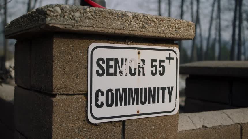 A community sign nailed to a stone pedestal connected to a wall