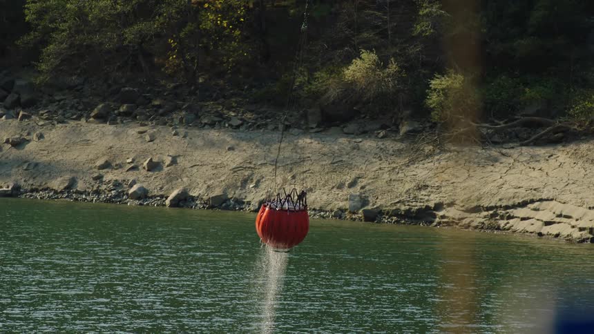 Helicopter bucket suspended on a cable carried by a helicopter to deliver water for aerial firefighting