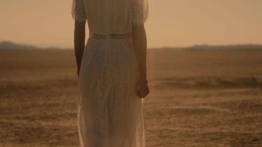 Woman with white dress walks in the desert