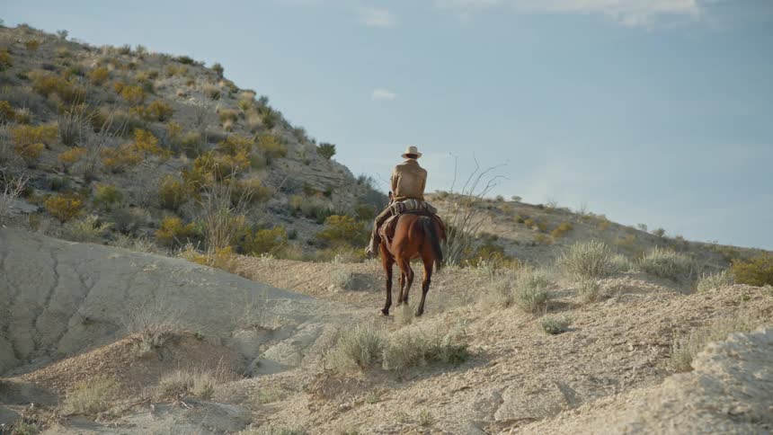 Cowboy rides along desert ridge