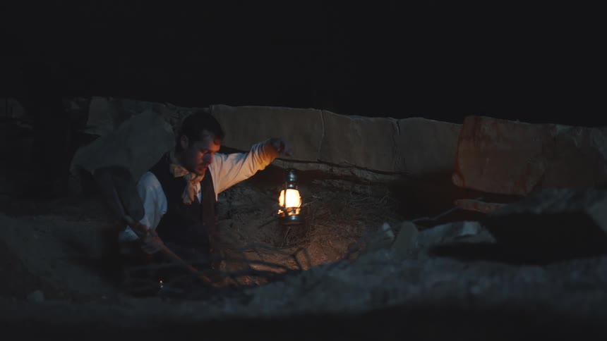 Man digs for treasure at night with lantern
