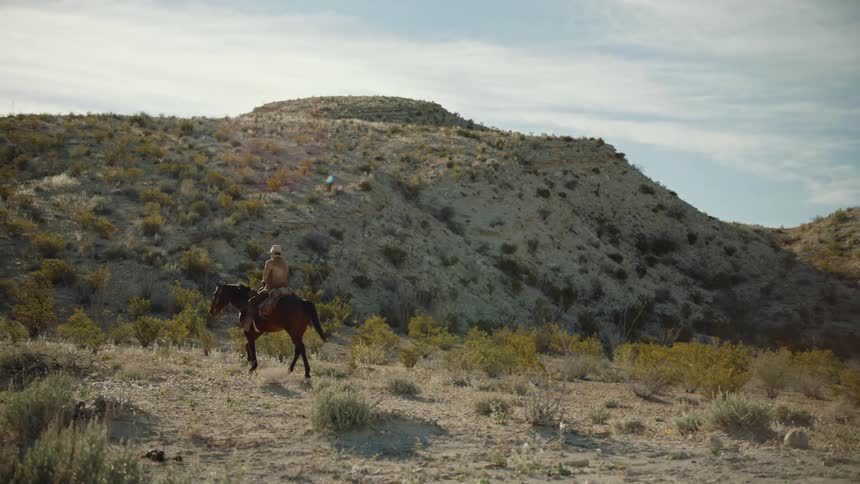 Cowboy rides through desert hills