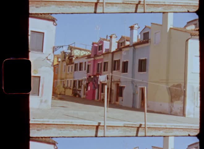 Looking into a small or narrow street or road with colorful facades of houses near the canals in Venice caught on vintage film on a bright sunny day with blue sky and no people