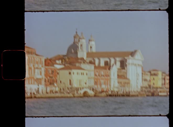 Vintage film footage of the impressive cathedral Santa Maria Del Rosario in Venice Italy viewed from a boat floating or riding on the water as the wind blows and small waves ripple the surface of the river or canal