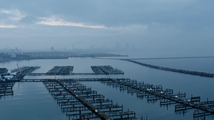 Empty marina in front of the faint silhouette of the city skyline behind the fog