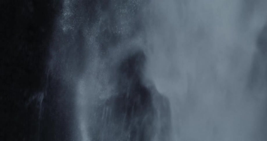 Waterfall forms whitewater while it falls down cliff