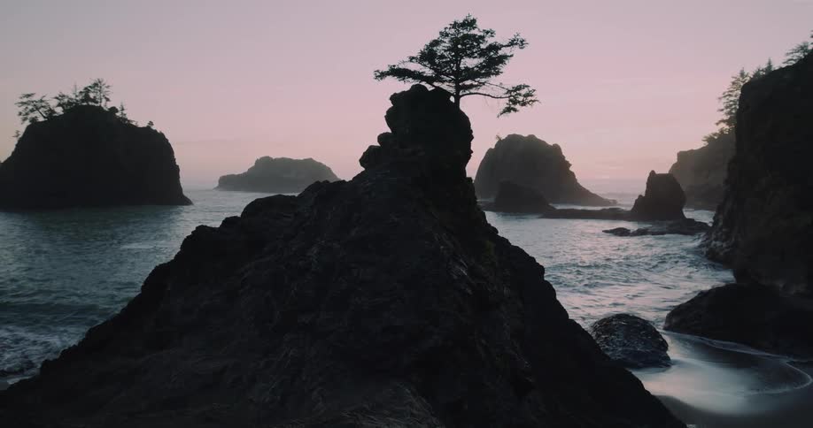 A coastline with large rocks throughout the waters and waves crashing against the coast