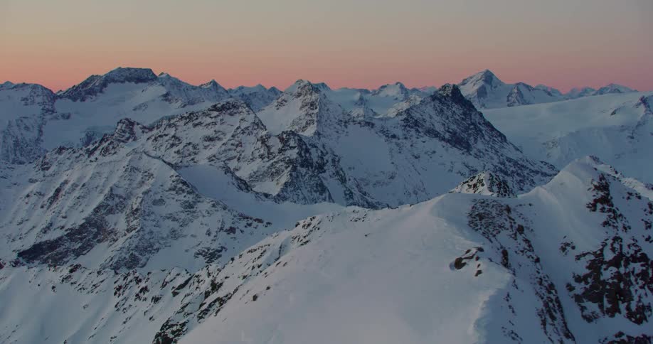 A snow covered mountain range in the evening
