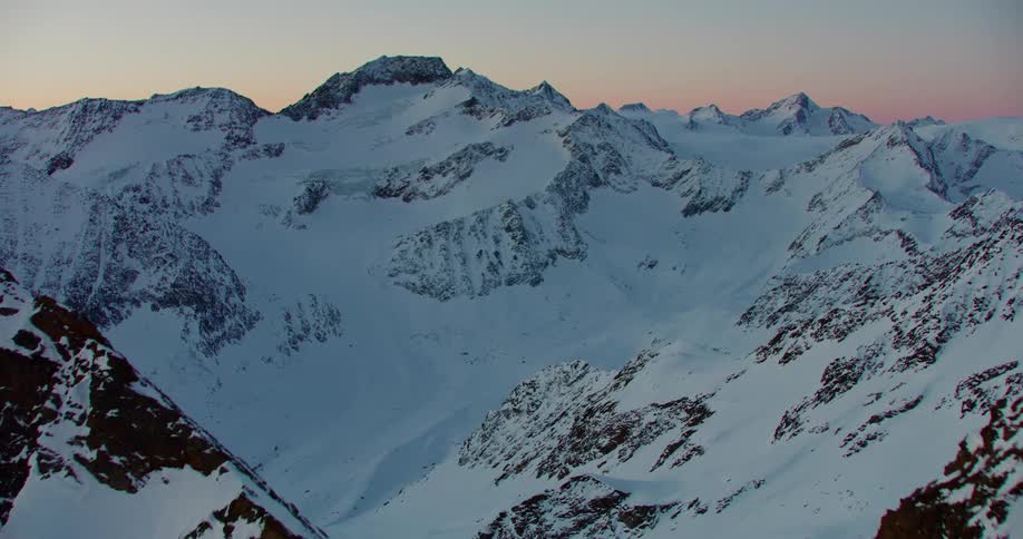 The camera flies over a snow covered and rocky mountain range