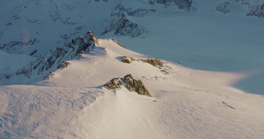 Rocky ridges of a mountain range are buried under a thick layer of snow