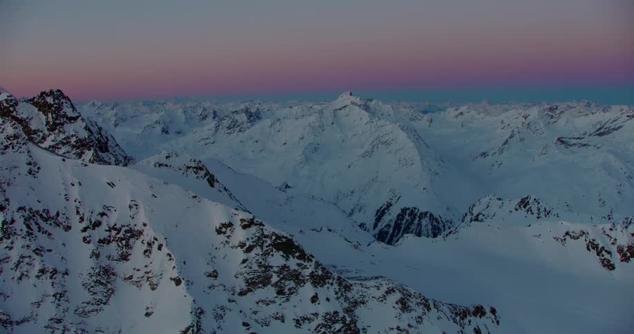 The sun sets over a snow covered mountain range