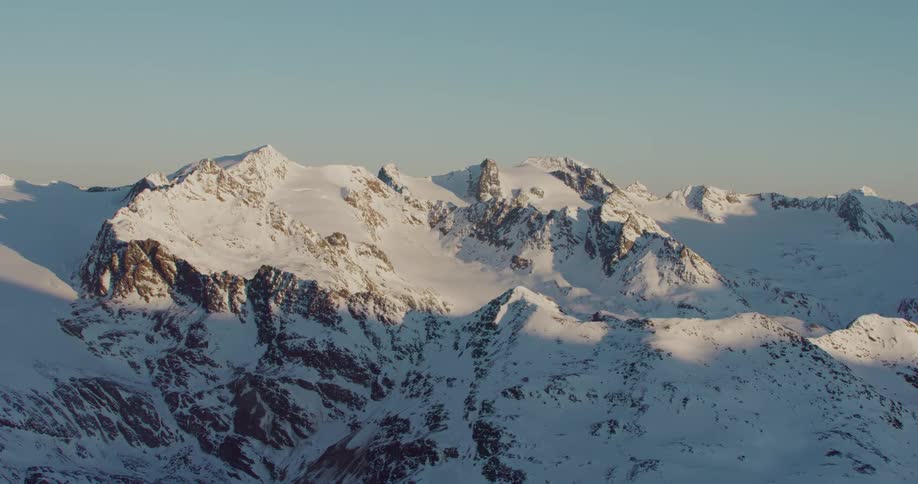 An aerial view of rocky mountain peaks on a snowy arctic landscape
