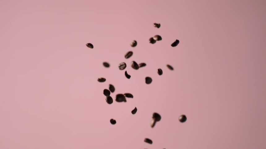 Coffee beans falling with a pink background