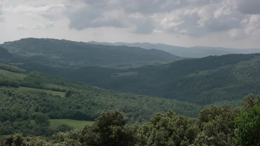 Gray clouds are hanging over a valley and hills
