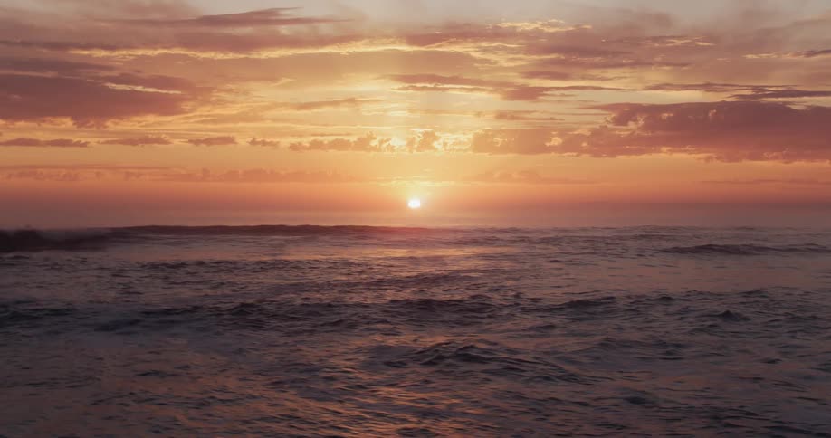 The sun is nearly set behind the ocean
