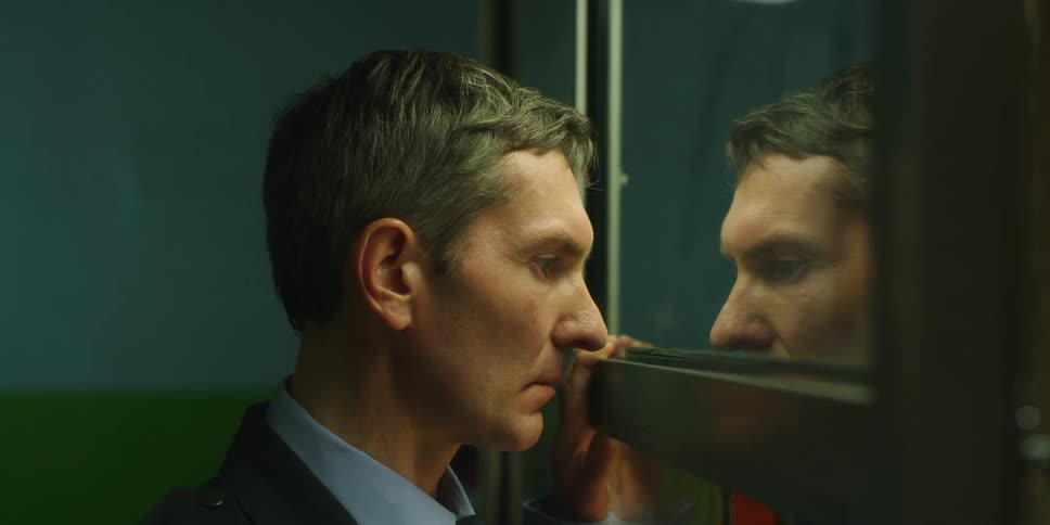 A man is looking close into the mirror