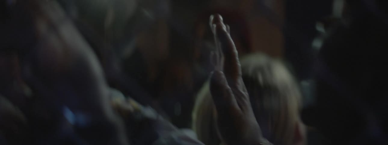 A person is being pressed against a fence at night