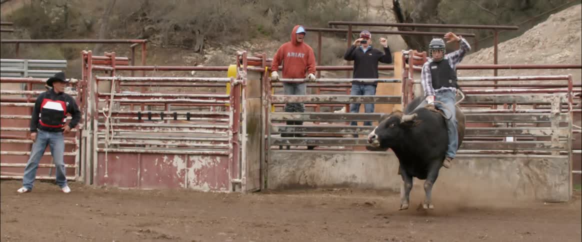 A cowboy rides a bull on a ranch