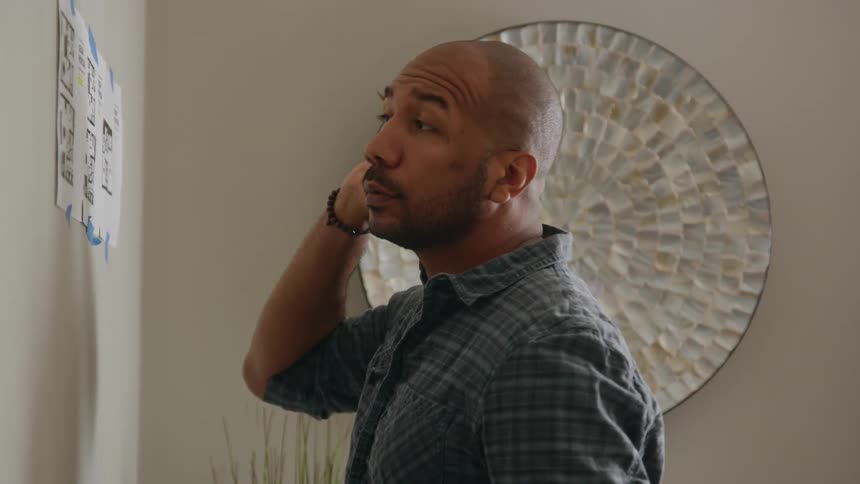 Man uses measuring tape to measure wall and writes numberon floor plan taped to the wall