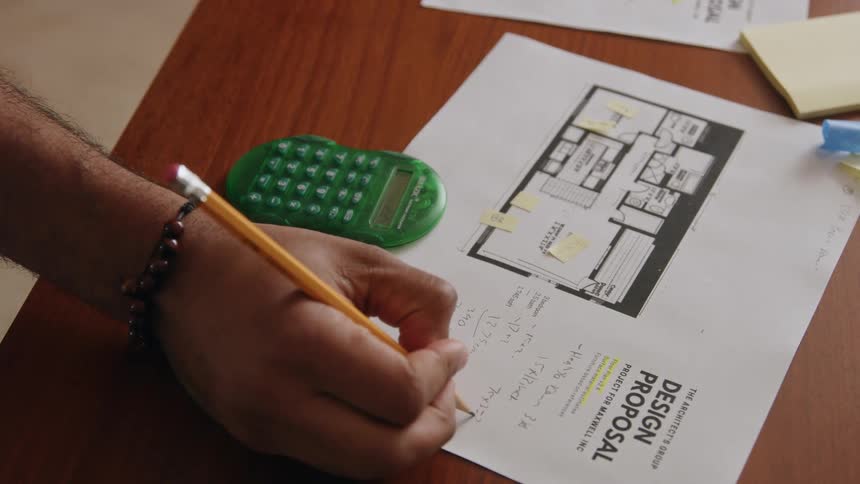 A persons hands writing with a pencil on a proposal paper then his face