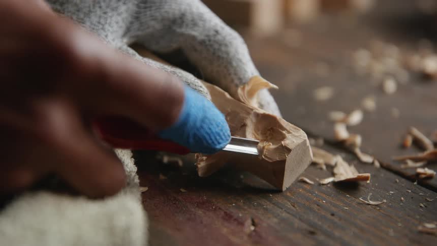A man is woodworking and gouging an area on a piece he is working on