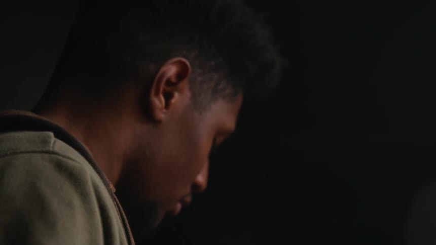 The view is of a young black man that is hanging out inside of his home