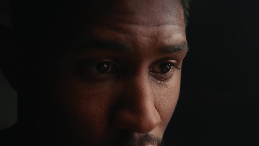 The view is of a young black man and is inside of his home