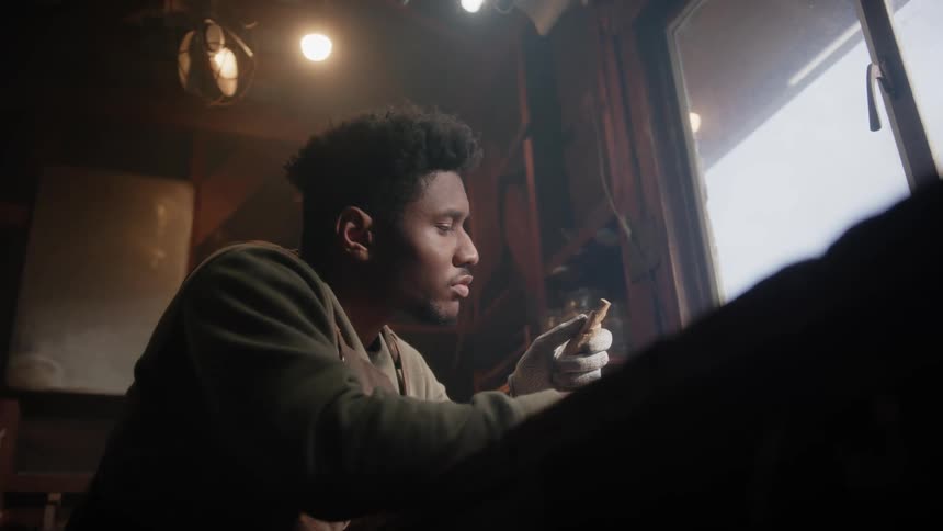 A young black man is sitting down indoors of his home