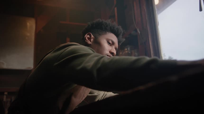 The view is of a young black man that is inside of his home