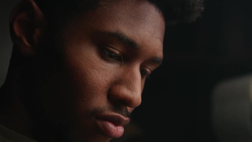 Light shines on the face of a man looking down