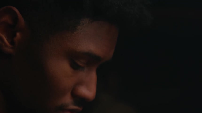 Light shines on the face of a man looking down and appears to be in deep thought