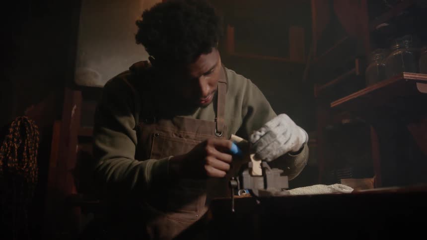 A young black man is working on something inside of his home