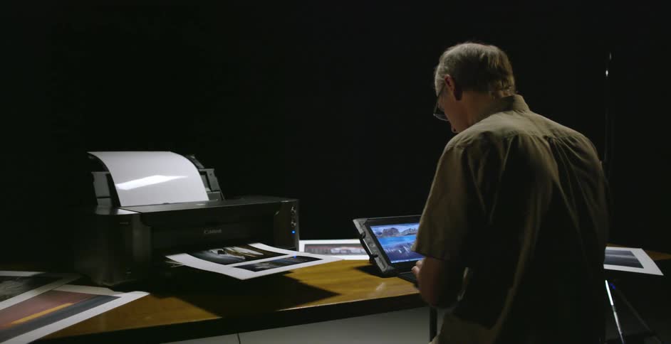 A man is drawing on a tablet and printing stuff