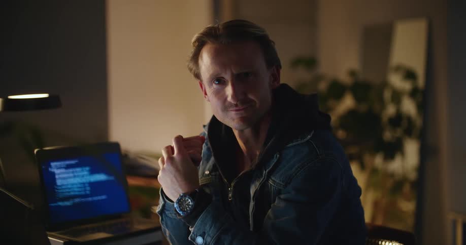 A man smiles by the computer