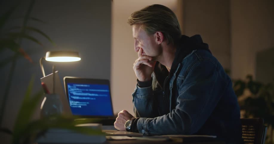 A man watches coding software on his computer