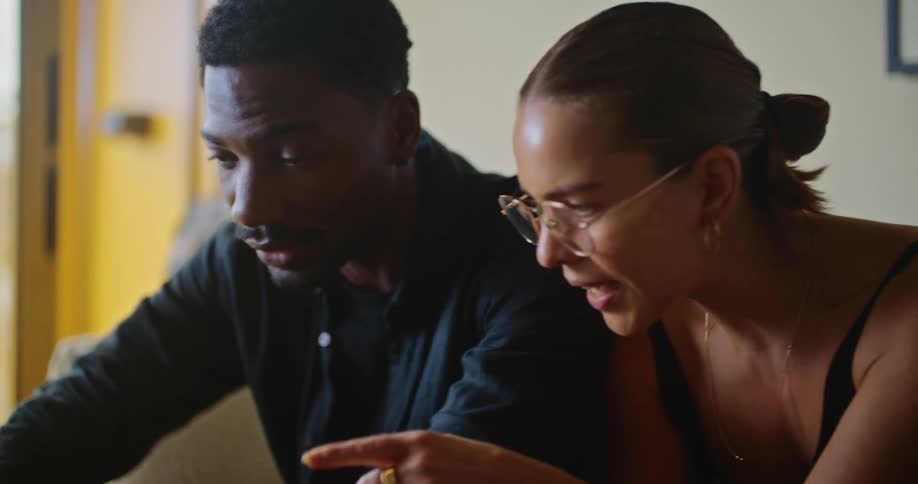 Man and woman talk about contents on laptop as man uses touch pad